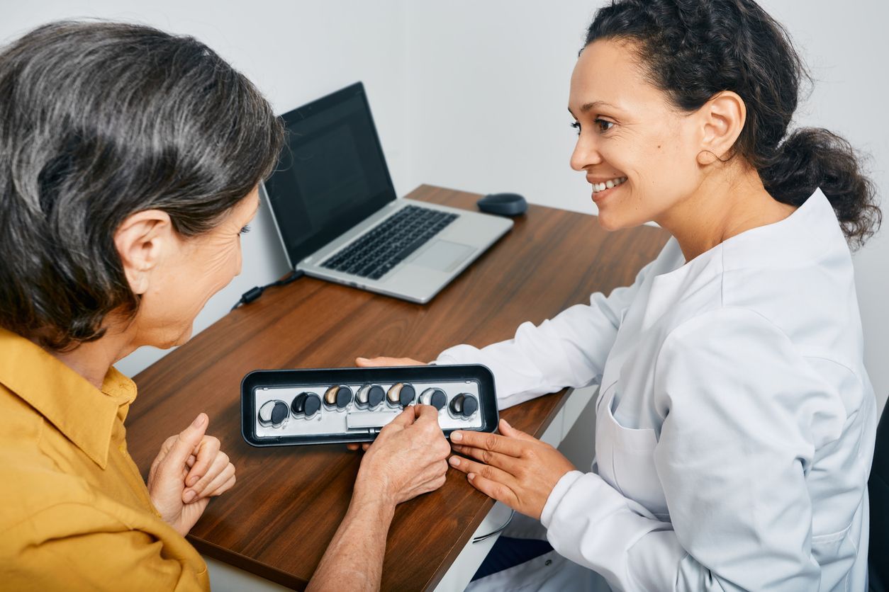 A woman is sitting at a table talking to a man about hearing aids.