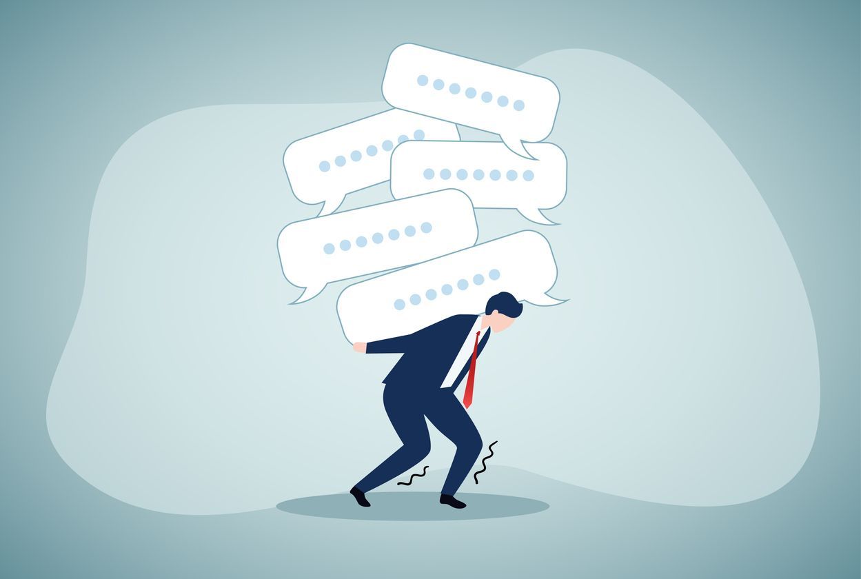 A man in a suit and tie is carrying speech bubbles on his back.
