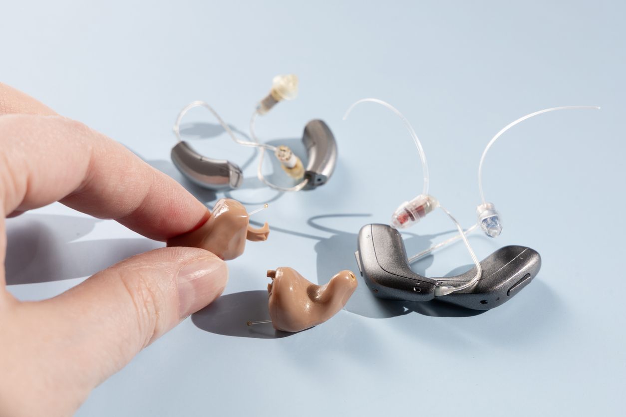 A person is holding a pair of hearing aids in their hand.