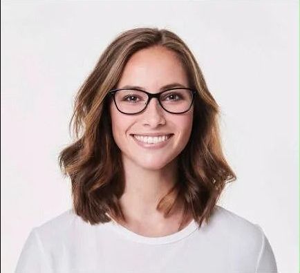 A woman wearing glasses and a white shirt is smiling.