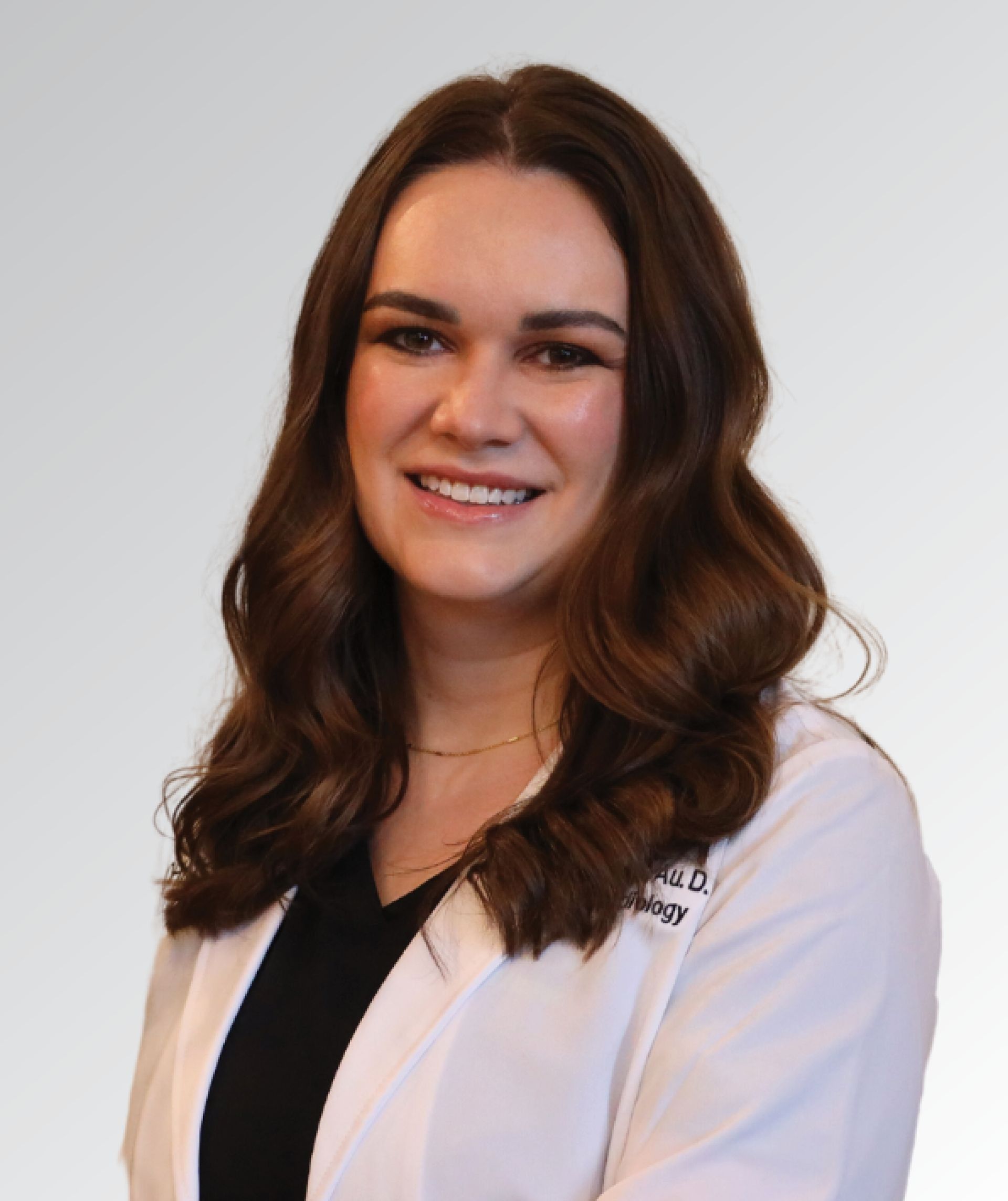 A woman in a white lab coat is smiling for the camera
