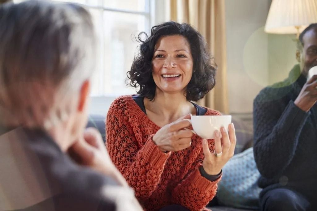 A woman is sitting on a couch holding a cup of coffee.