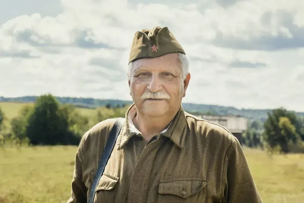 A man in a military uniform is standing in a field.