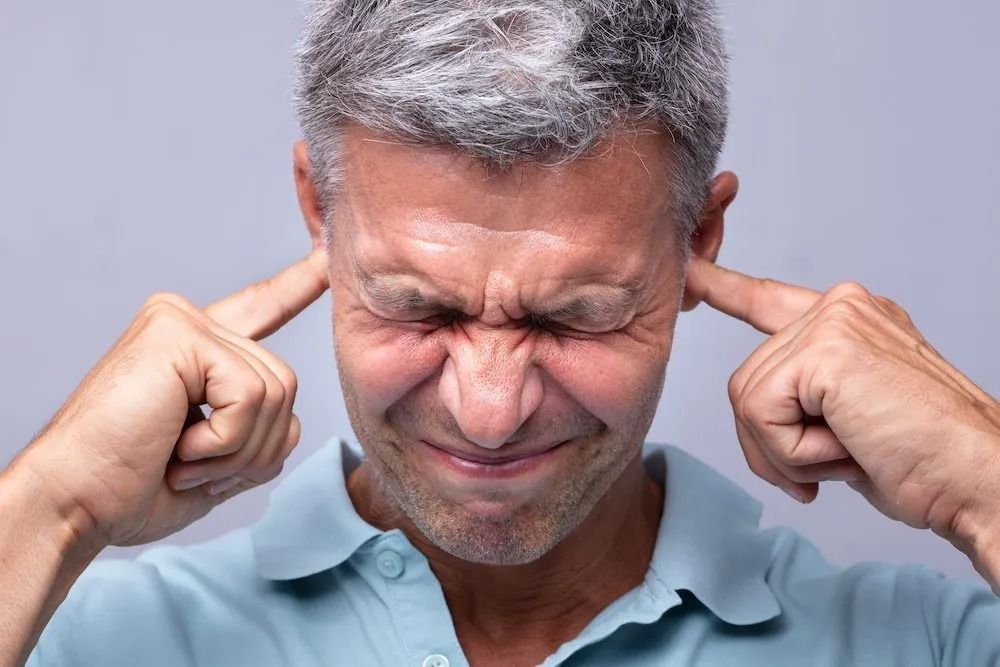 A man is covering his ears with his hands.