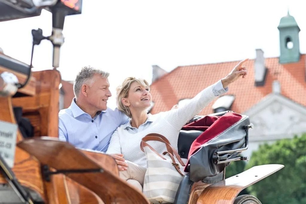 A man and a woman are riding in a horse drawn carriage.