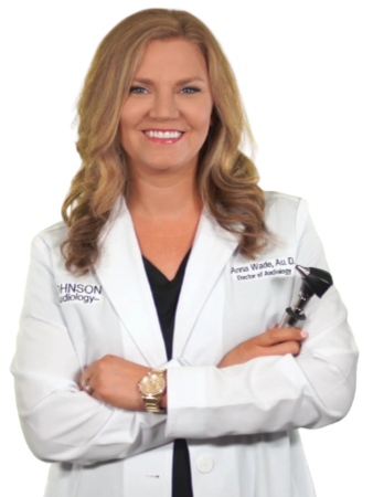 A woman in a white lab coat is smiling and holding an otoscope
