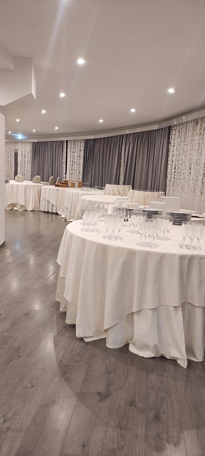 Una grande stanza piena di tavoli e bicchieri.