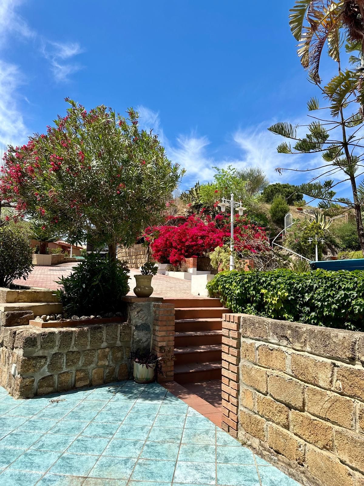 Un muro di mattoni con scale che portano a un giardino con fiori e alberi.