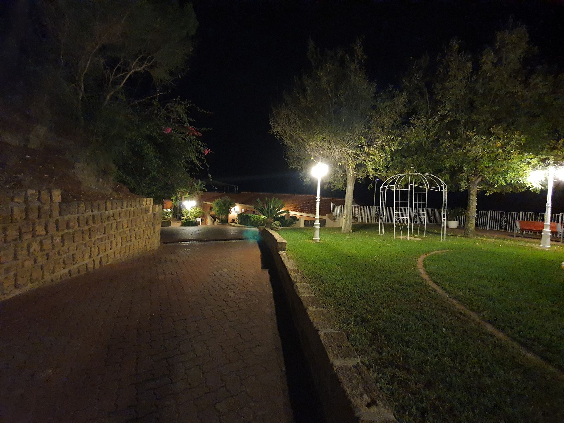 Una passerella in mattoni che conduce a un parco giochi di notte.