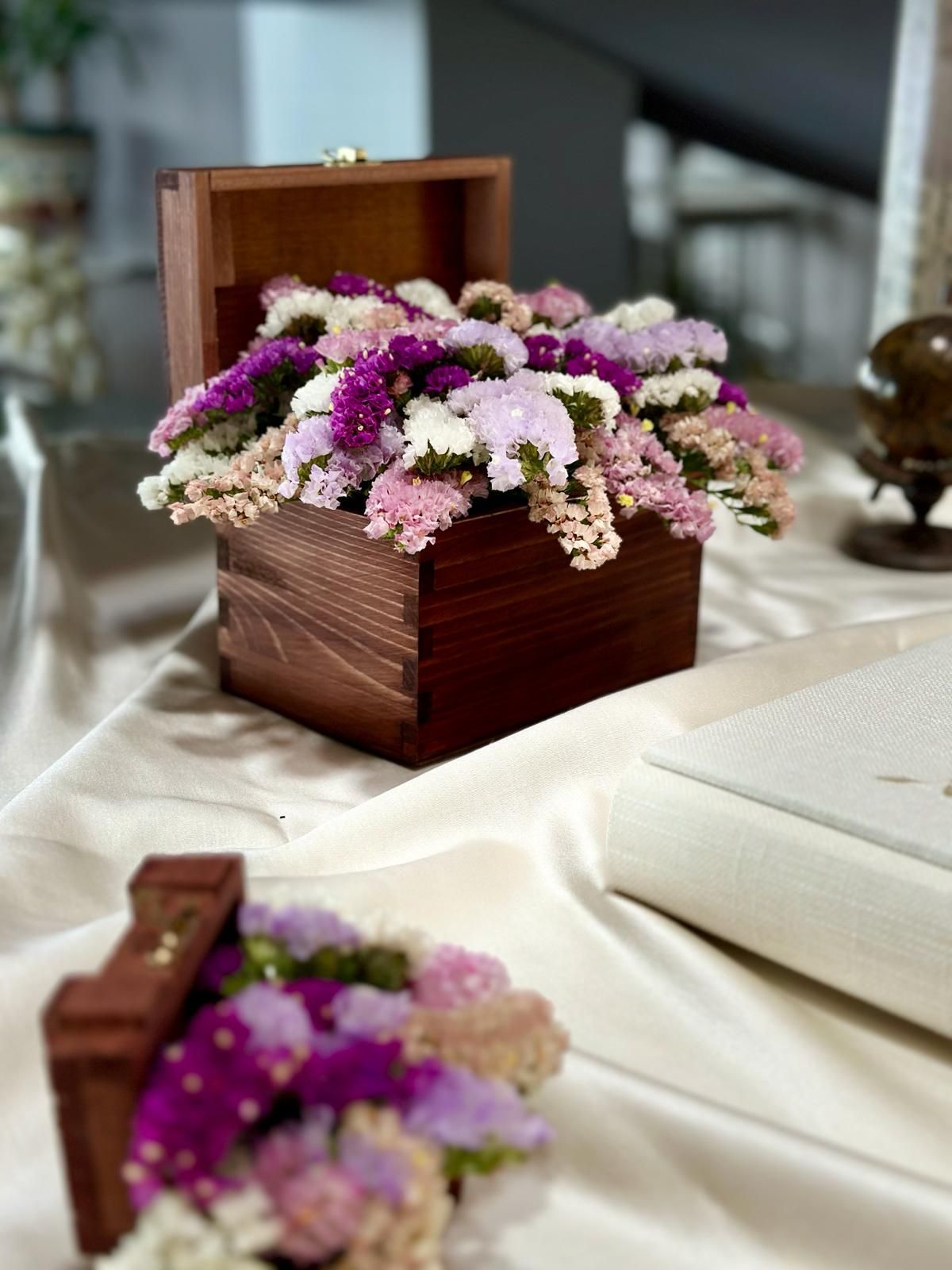 Su un tavolo è appoggiata una scatola di legno piena di fiori viola e rosa.