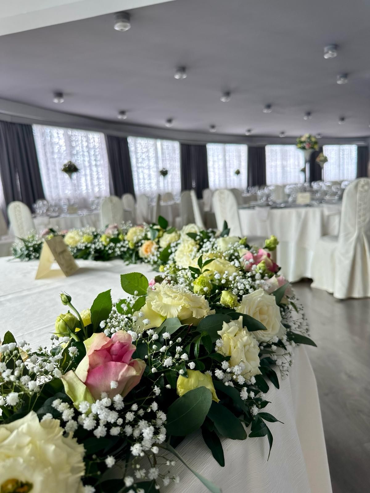 Un tavolo con dei fiori in una stanza con tavoli e sedie.