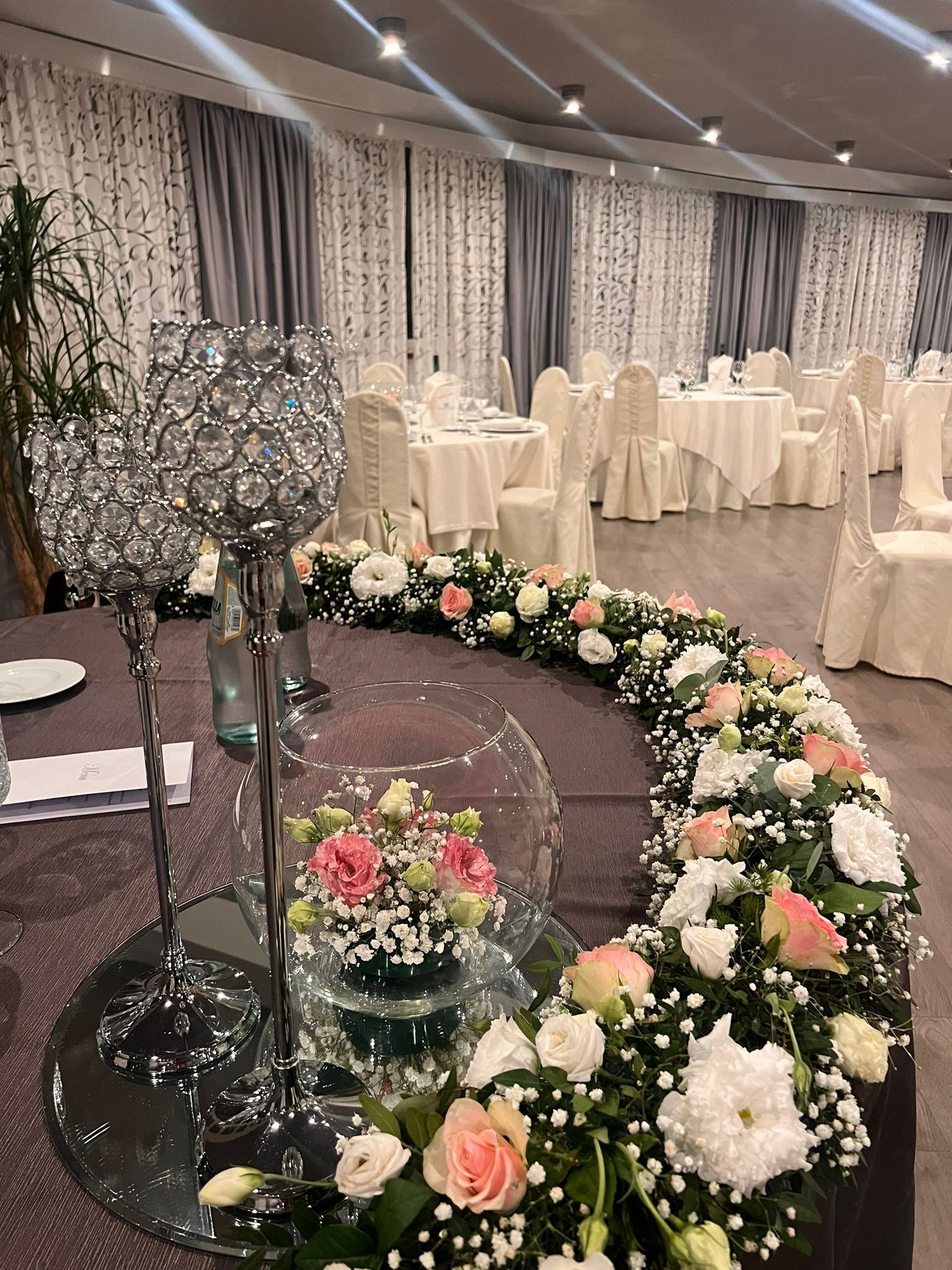 Una stanza piena di tavoli e sedie decorati con fiori e cristalli.