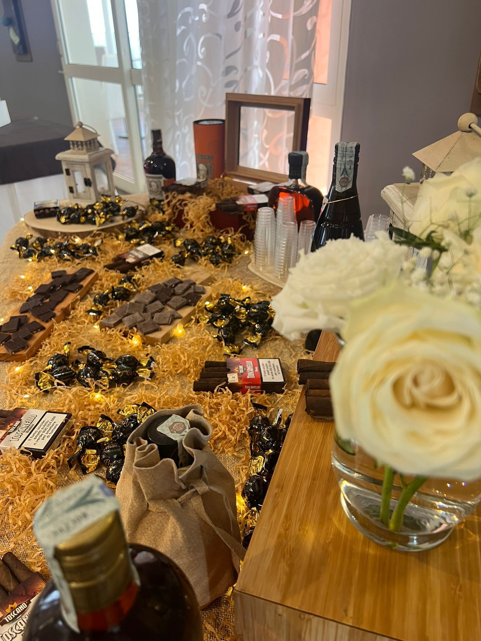 Un tavolo con sopra un vaso di fiori e bottiglie di alcolici.