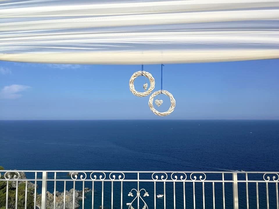 Un balcone con vista sull'oceano con due fedi nuziali appese al soffitto.