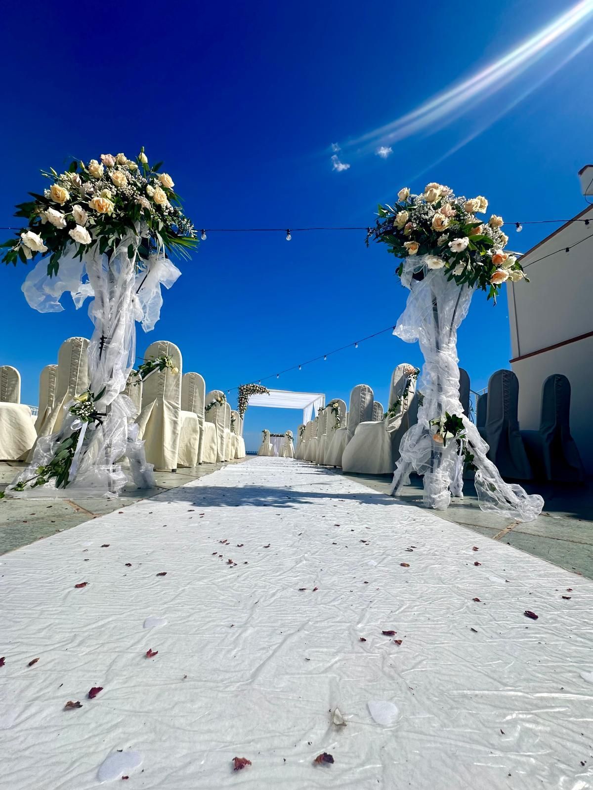 Una navata nuziale è decorata con sedie bianche e fiori