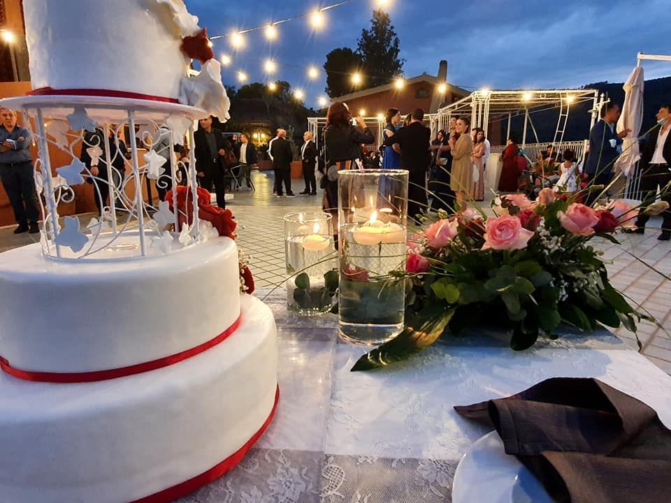 Una torta nuziale è appoggiata su un tavolo con candele e fiori.