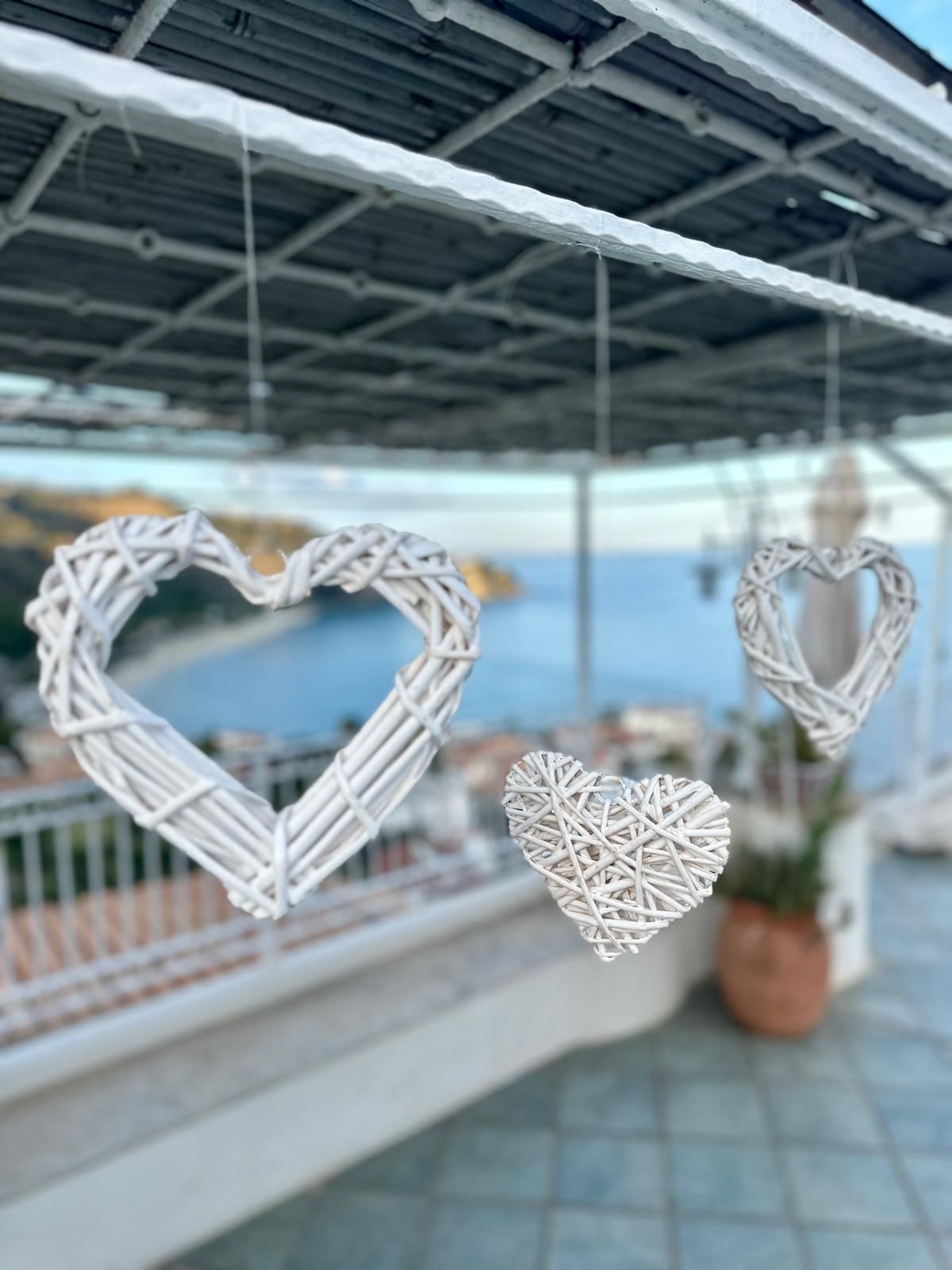 Tre cuori bianchi di vimini sono appesi a un tetto che si affaccia sull'oceano.