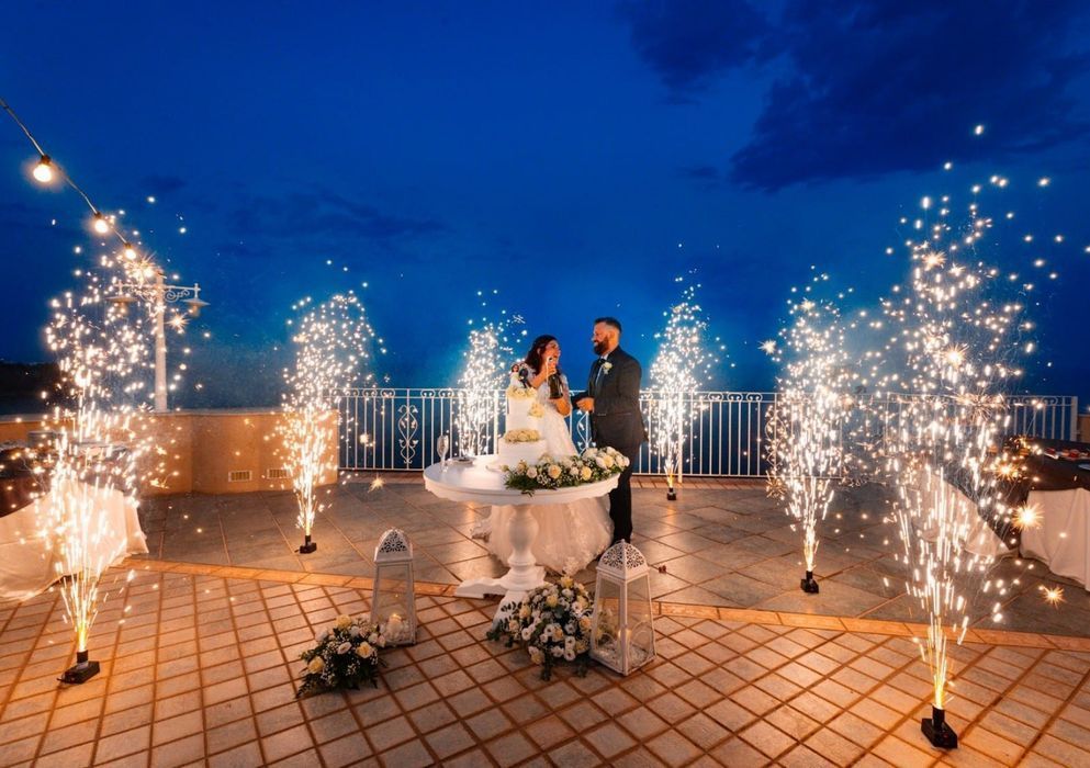 Gli sposi tagliano la torta nuziale davanti alle fontane luminose.