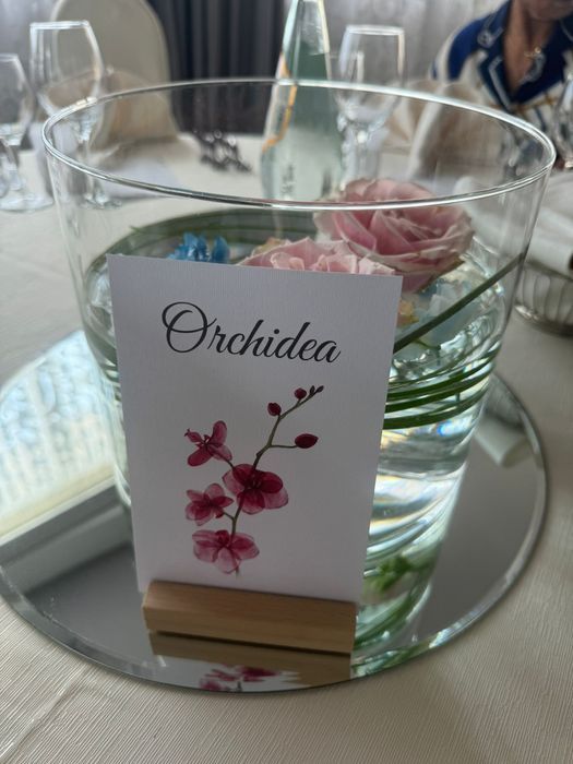Una ciotola di vetro con dei fiori dentro e un cartello che dice orchidea