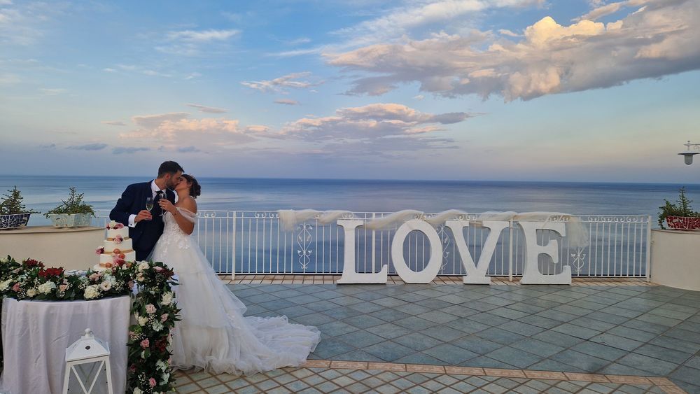 Una sposa e uno sposo si baciano davanti a un grande cartello con la scritta 