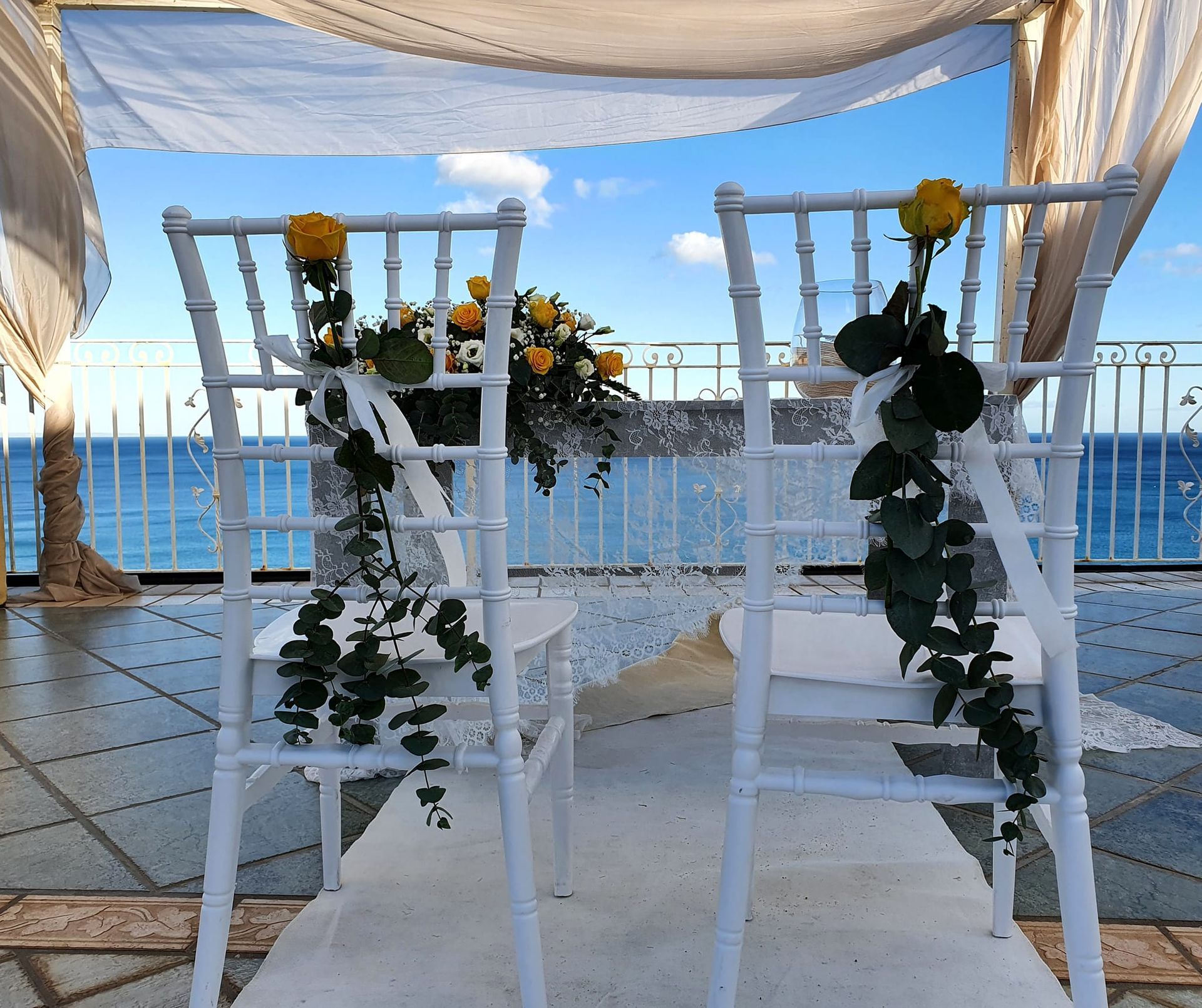 Un paio di sedie bianche con fiori sopra di fronte all'oceano