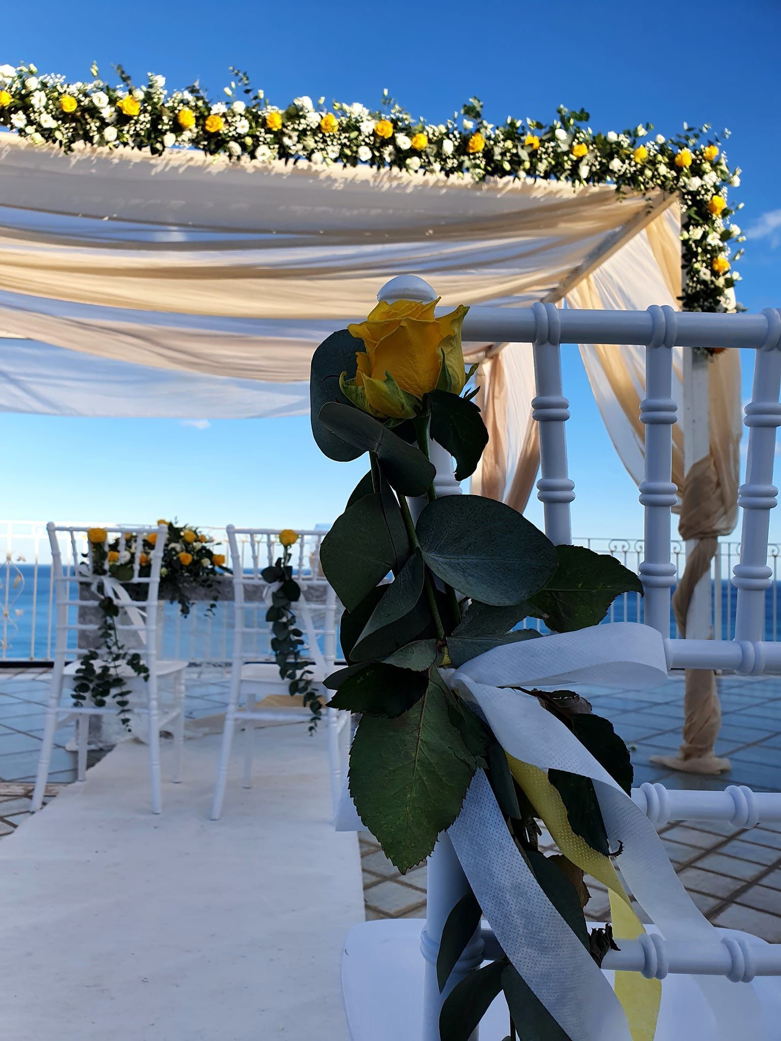 Una fila di sedie è decorata con fiori e nastri per una cerimonia nuziale.