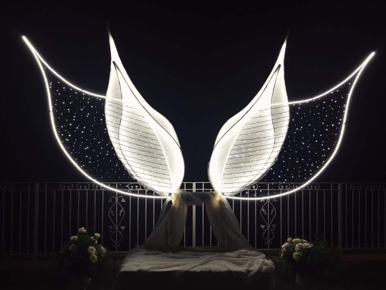 Una statua di ali è illuminata di notte