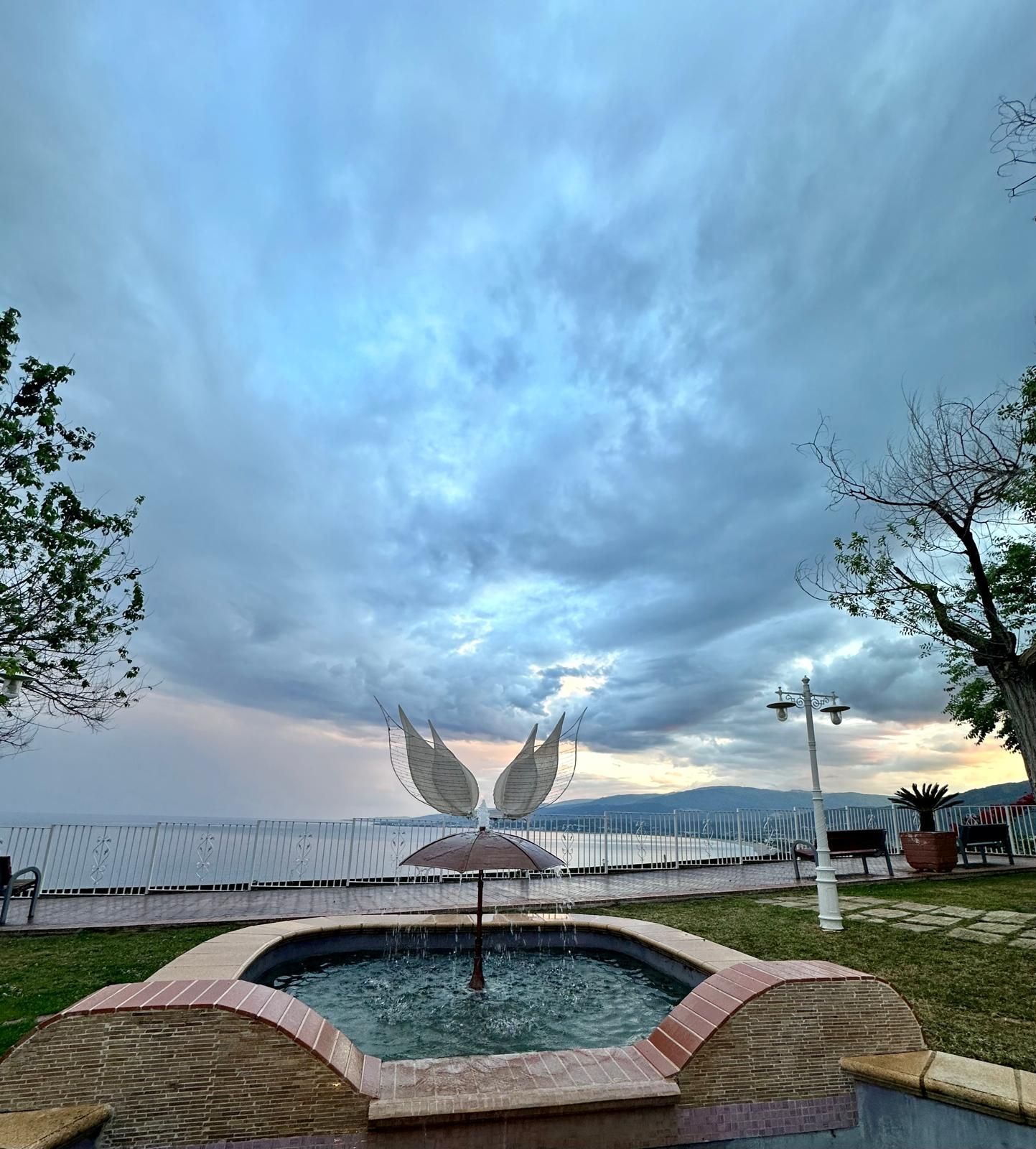 Una fontana in un parco con la statua di un uccello con le ali.