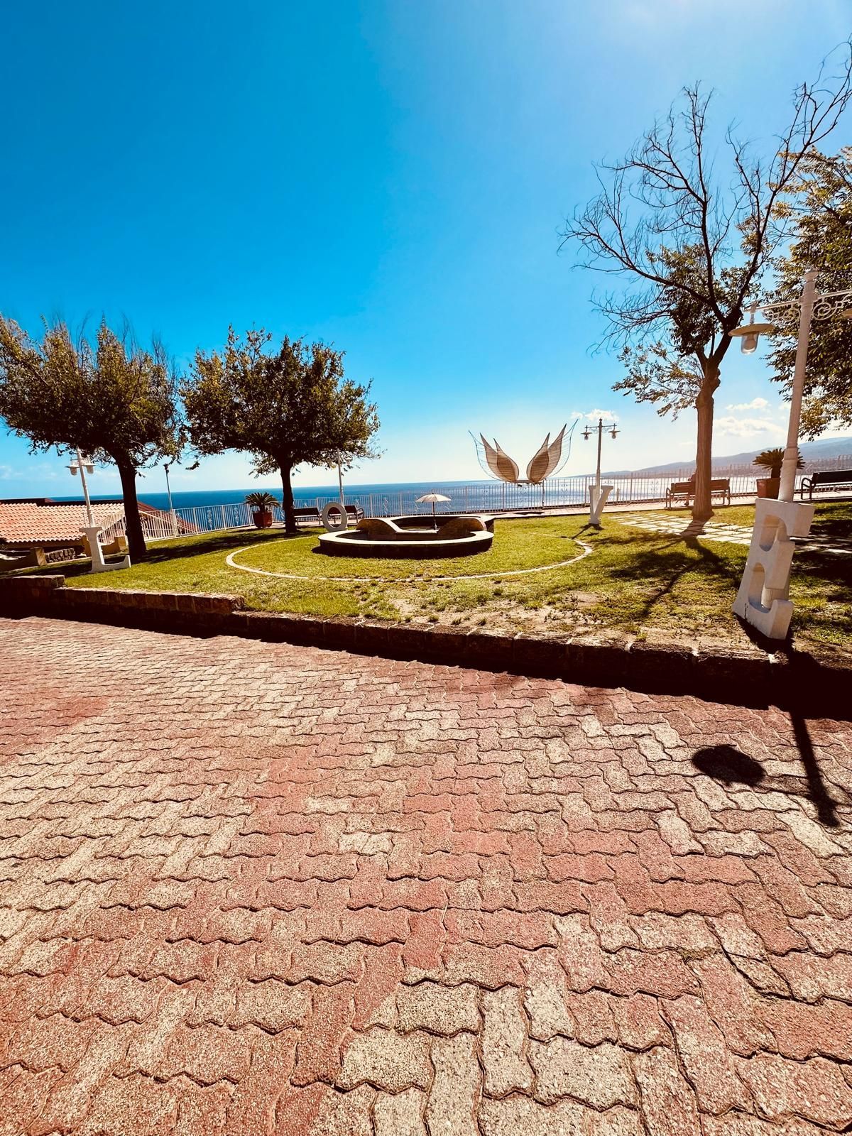 Una passerella di mattoni che conduce a una spiaggia con una chitarra in primo piano.