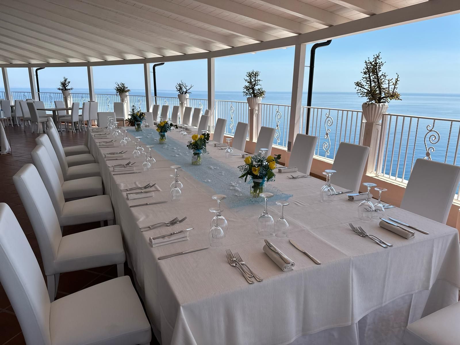 Un lungo tavolo con una tovaglia bianca e dei fiori sopra