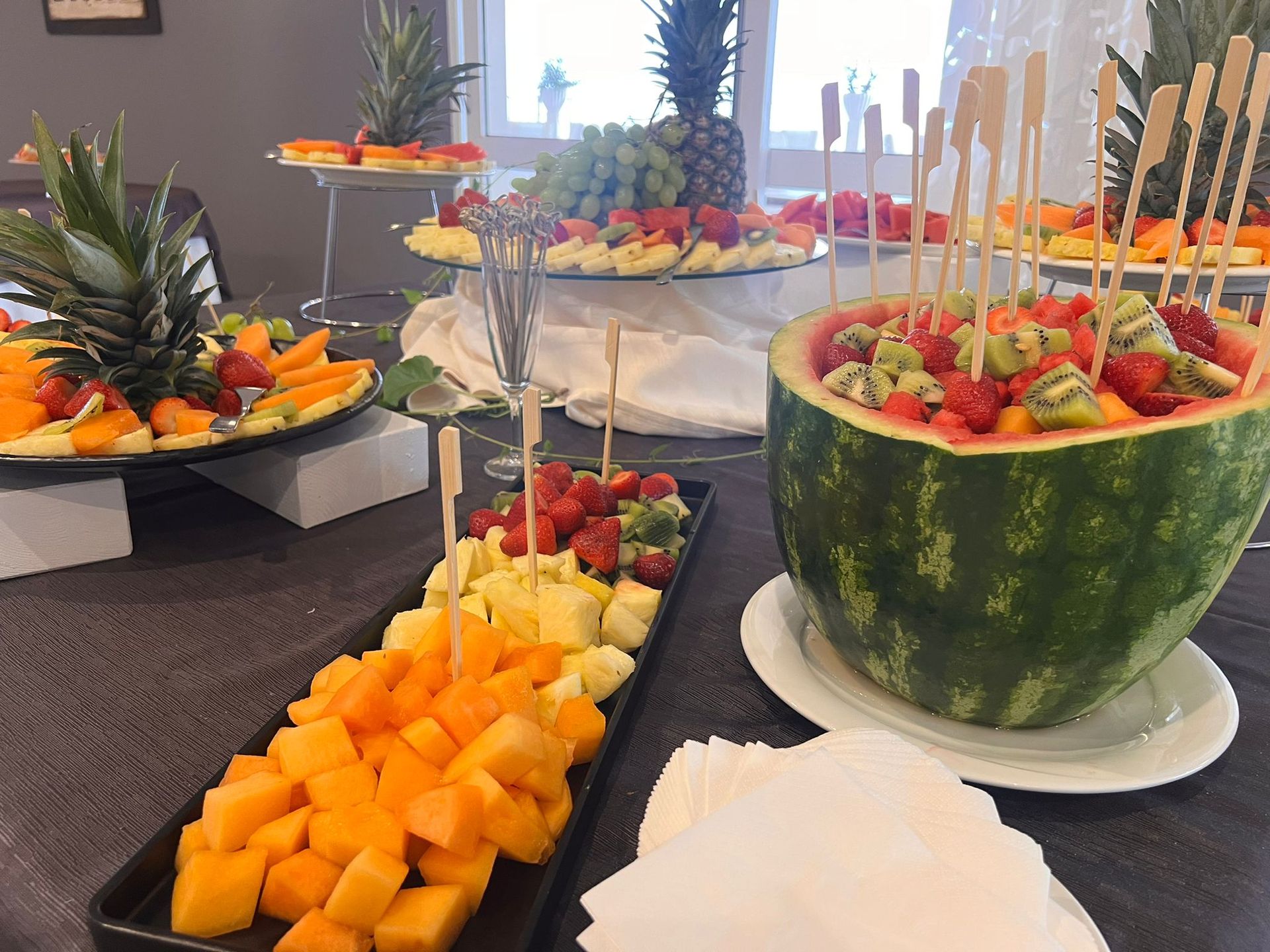 Un'anguria piena di frutta si trova su un tavolo accanto a un vassoio di frutta.