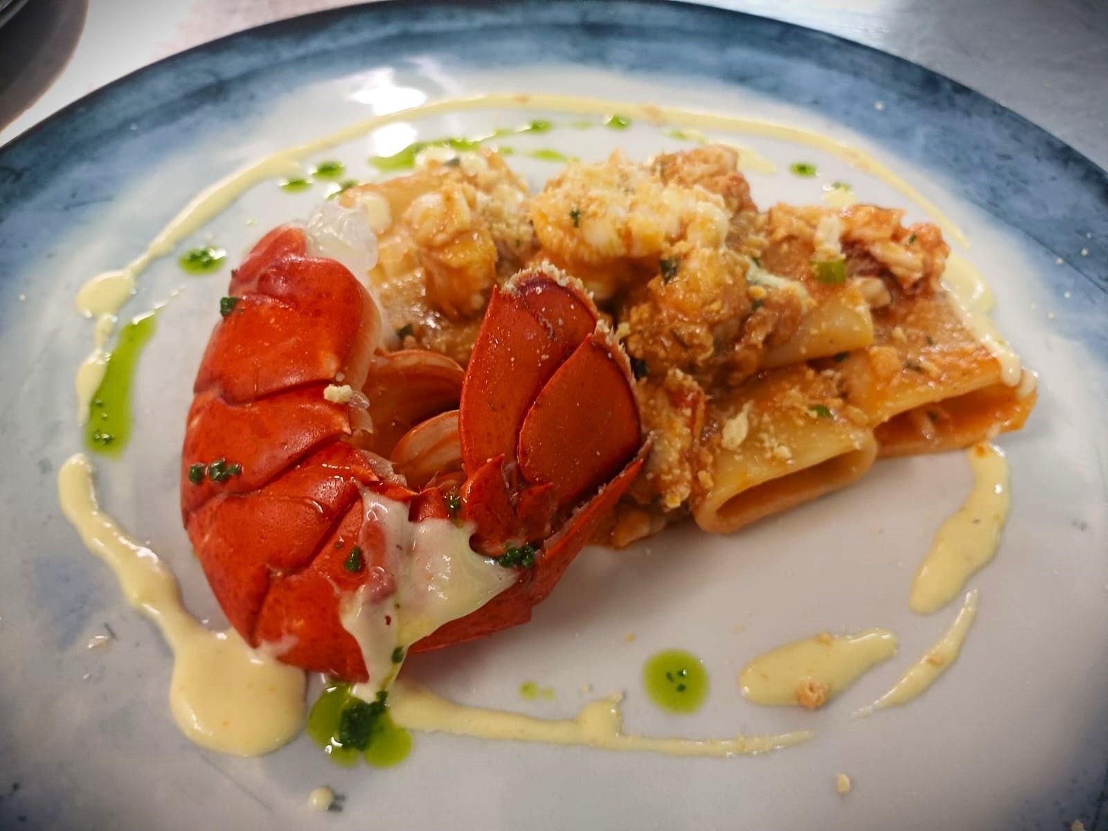 Un primo piano di un piatto di cibo con una coda di aragosta sopra.