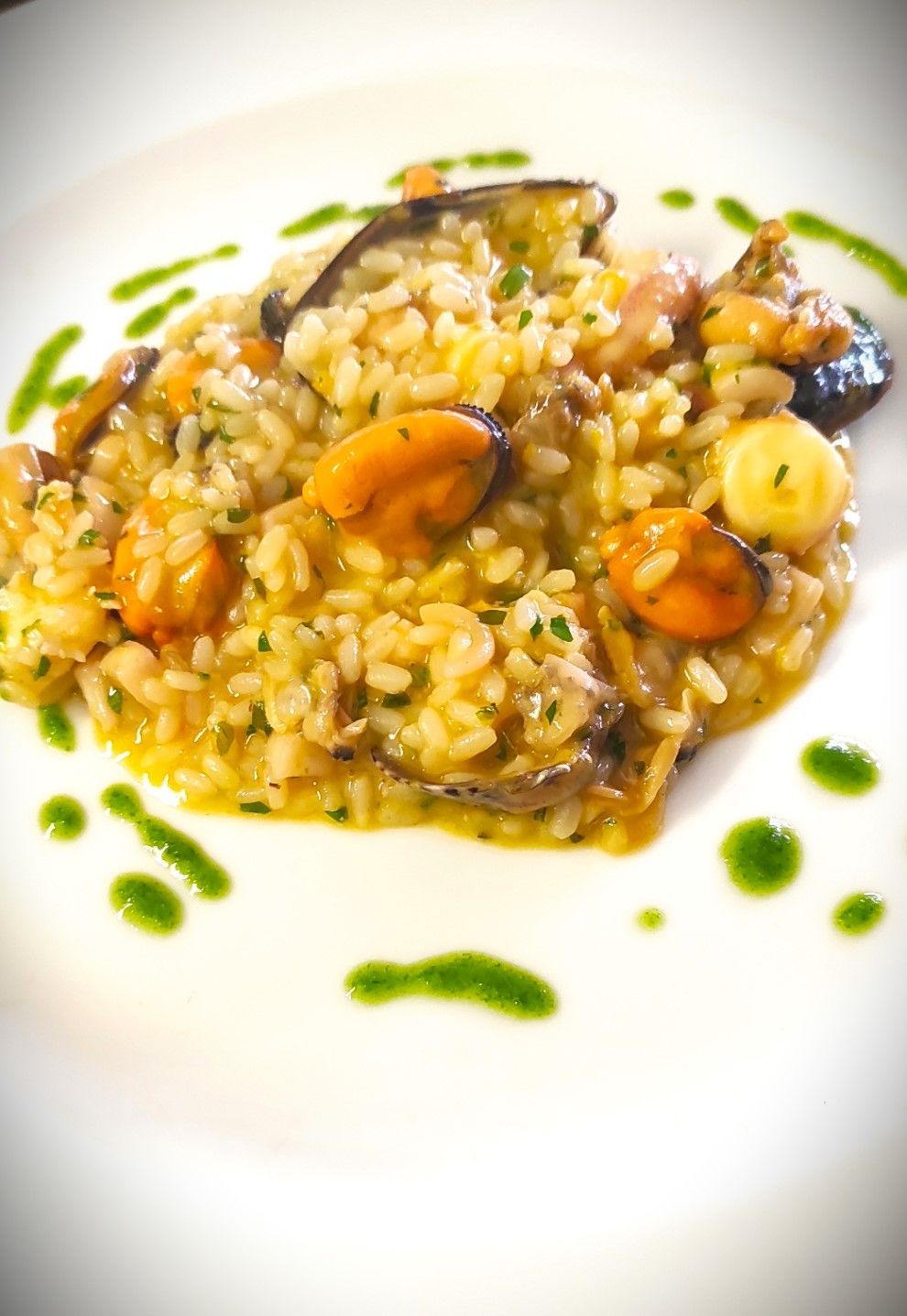 Un piatto bianco con riso e frutti di mare con salsa verde