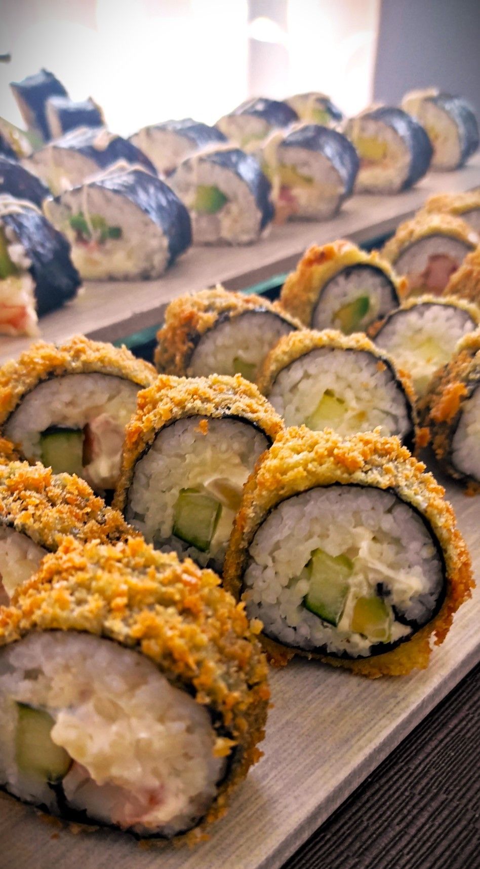 Un vassoio di rotoli di sushi fritti su un tavolo di legno.