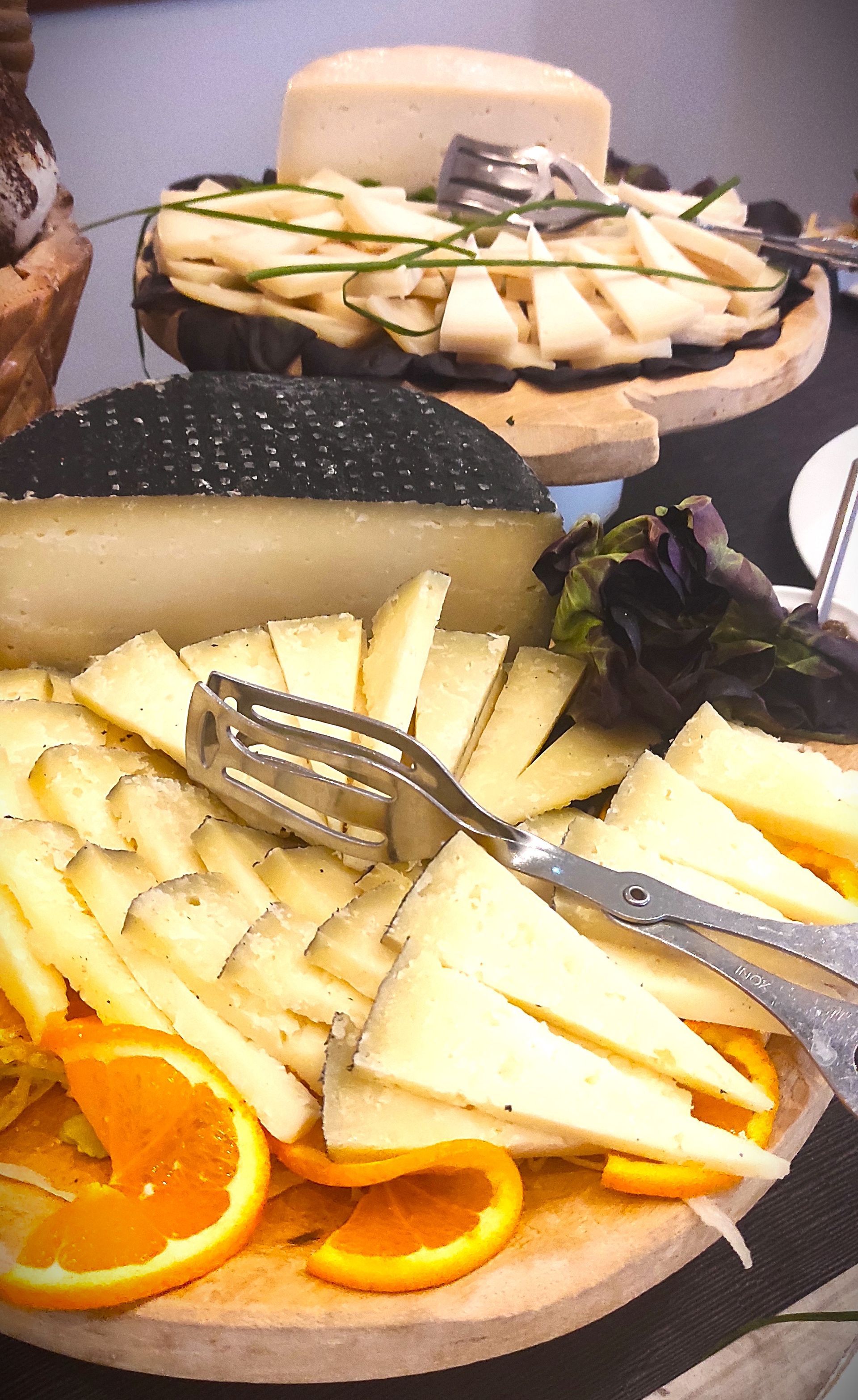 Un vassoio di formaggio e arance con pinze su un tavolo