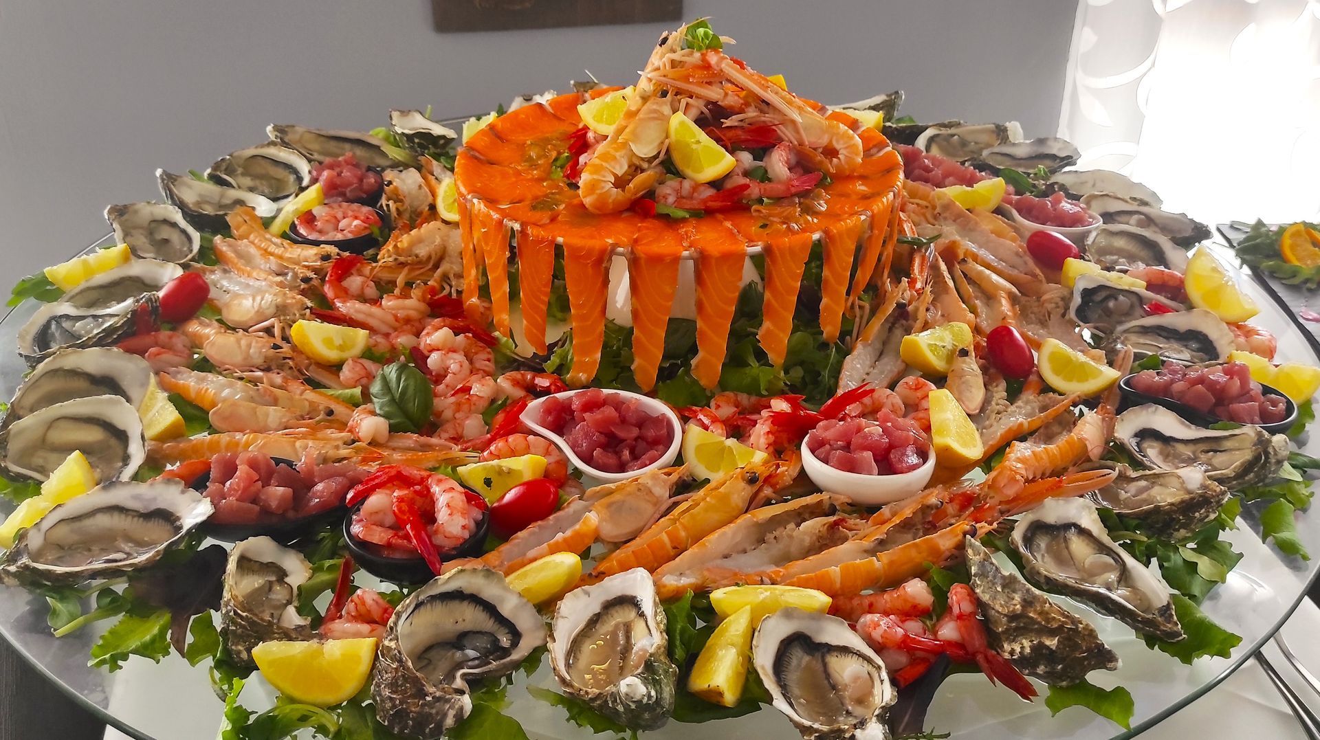 Un piatto di cibo con ostriche, gamberi e altri frutti di mare su un tavolo.
