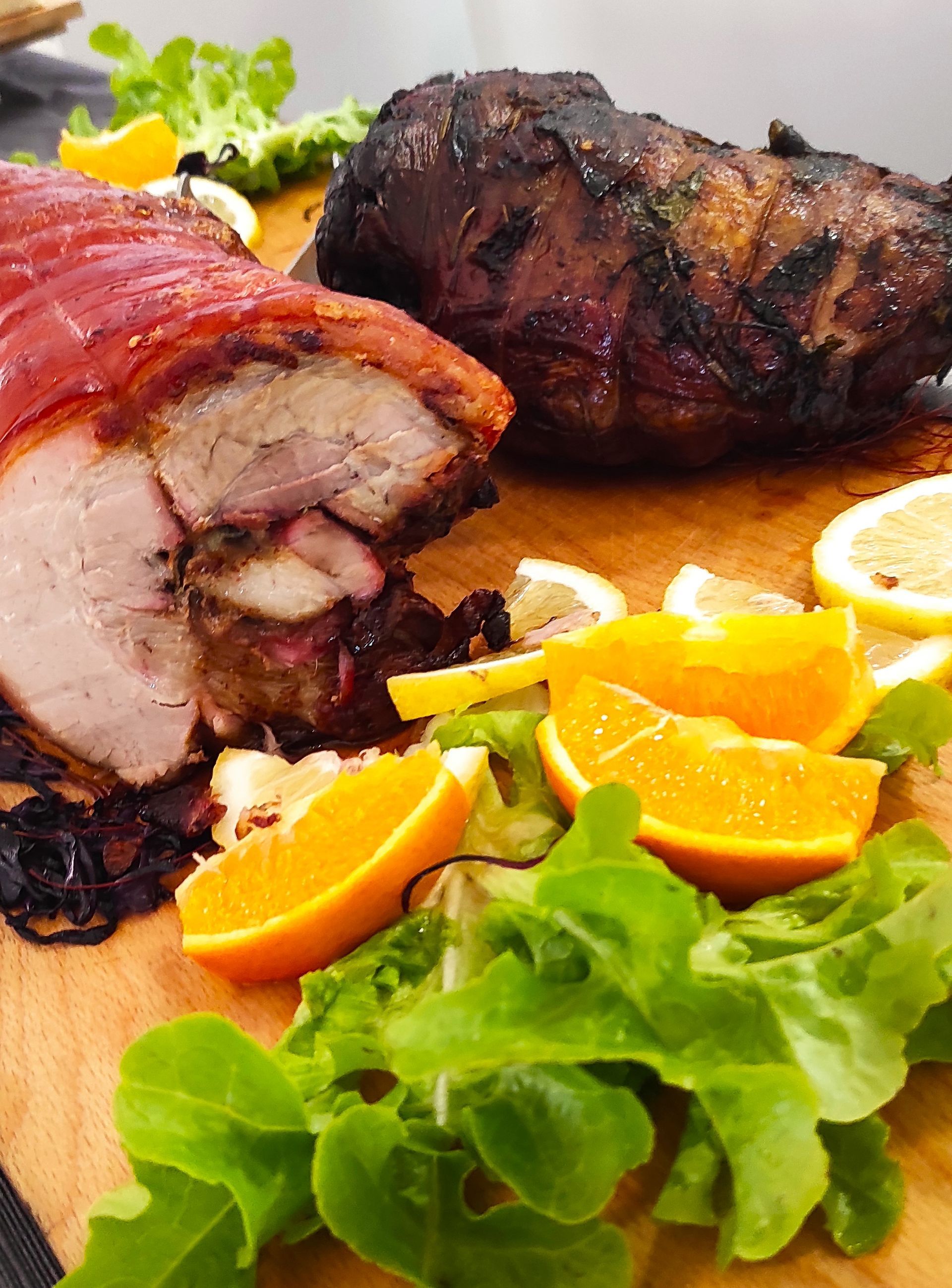 Un tagliere con sopra carne, arance, limoni e lattuga.