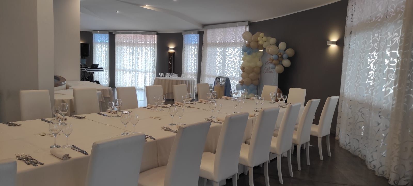 Una grande sala con tavoli e sedie allestita per un ricevimento di nozze.