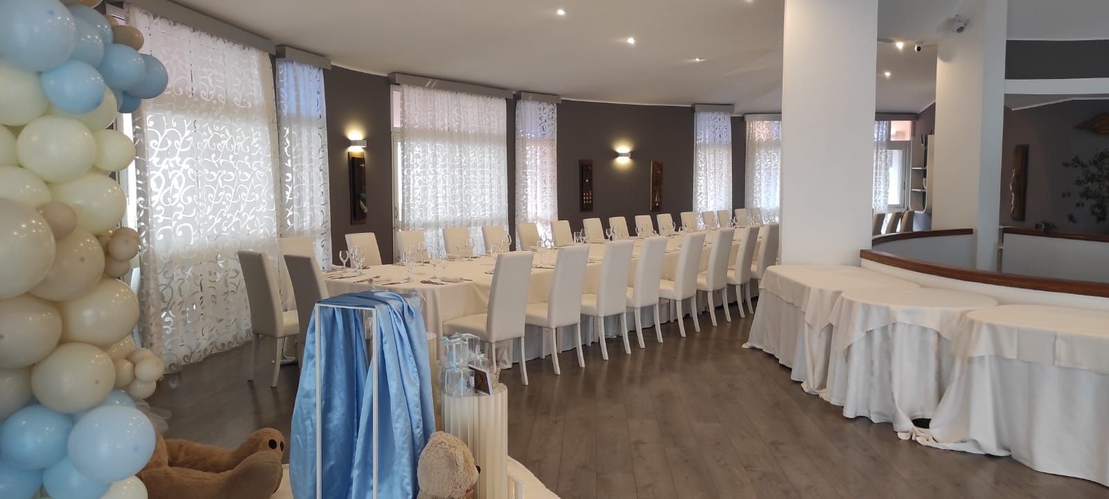 Una grande stanza piena di tavoli, sedie e palloncini.