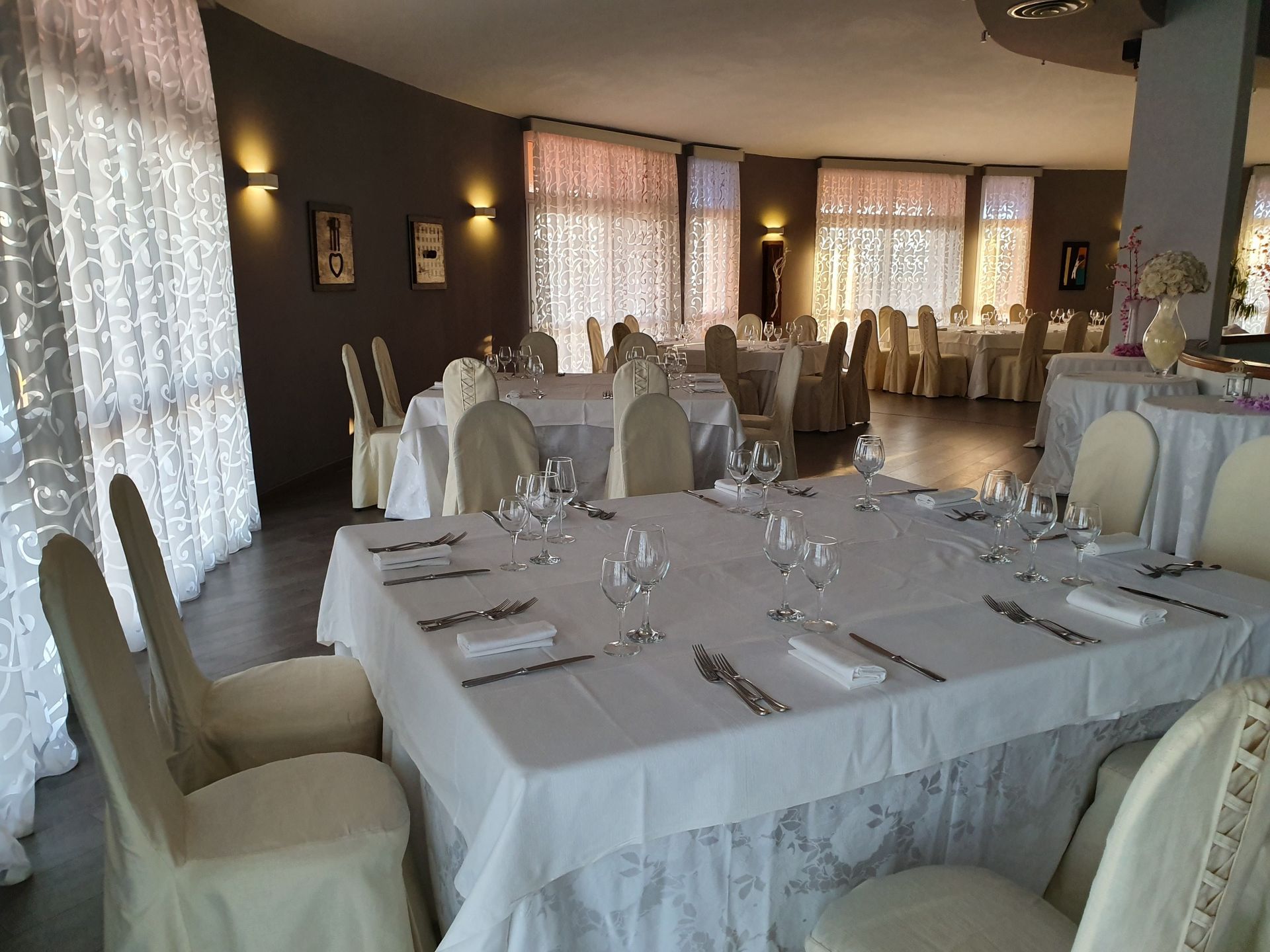 Una grande sala con tavoli e sedie allestita per un ricevimento di nozze