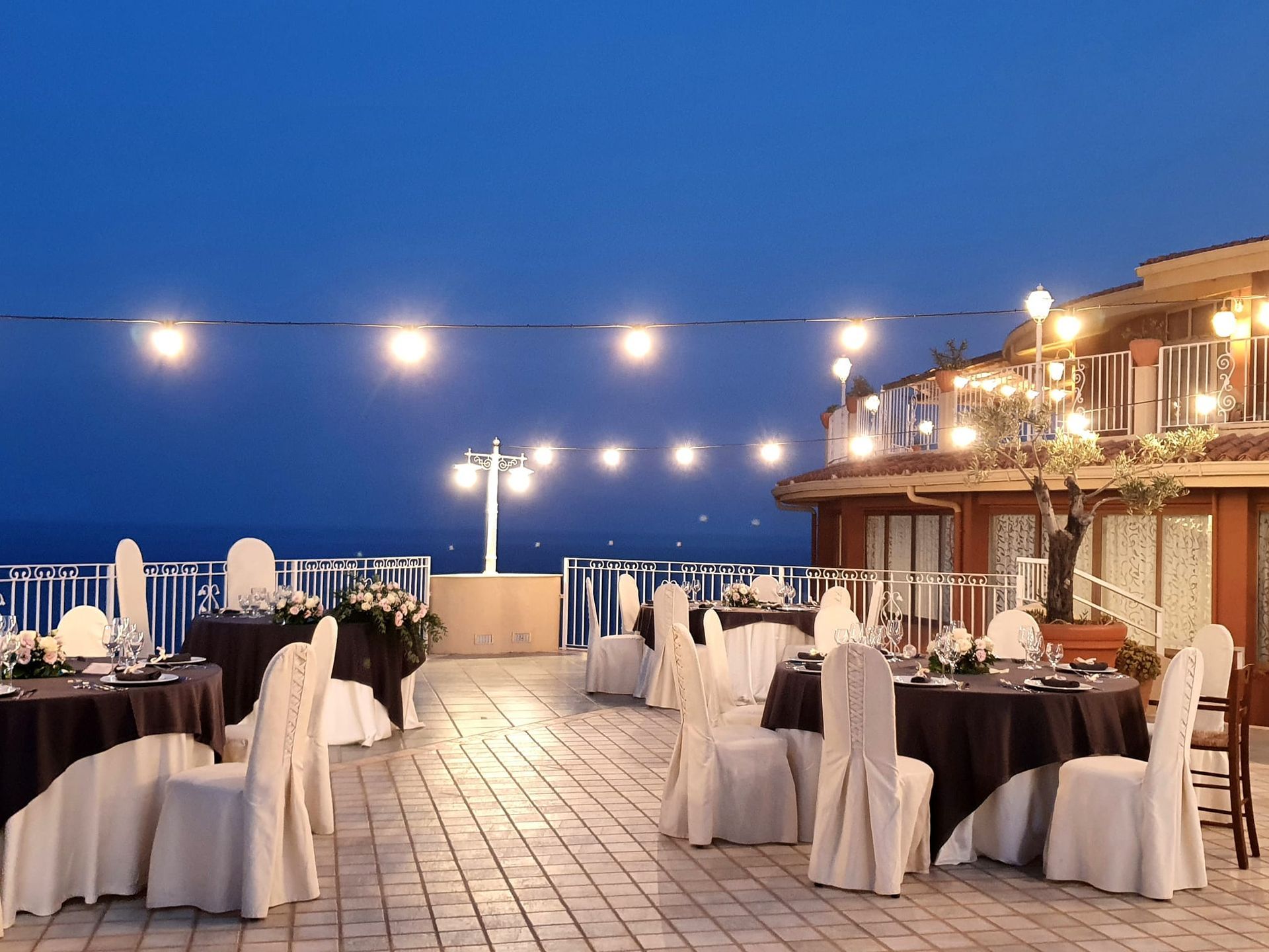 Tavoli e sedie sono sistemati su un patio con vista sull'oceano