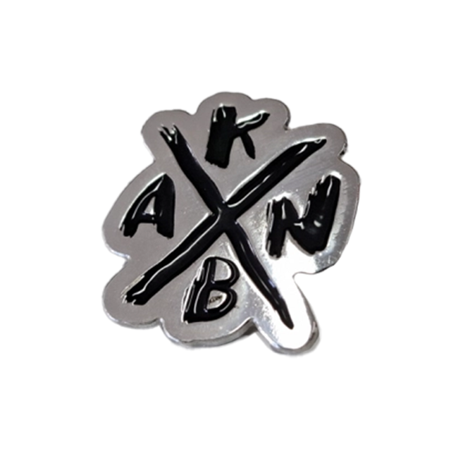 Silberne Anstecknadel mit einem schwarzen X in der Mitte und den Buchstaben A, K, B, N.