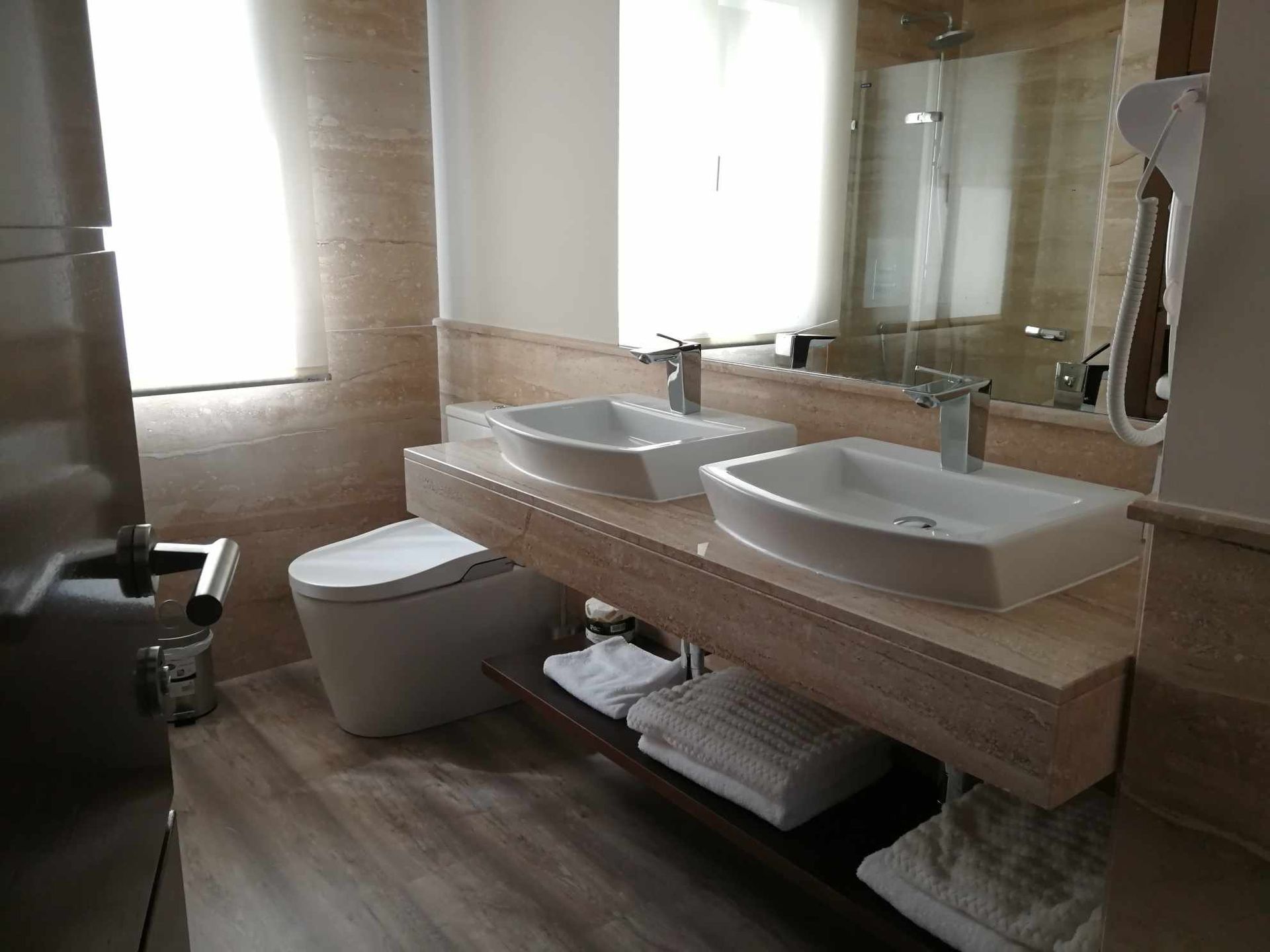 Baño moderno con lavabo doble flotante, inodoro y espejo grande.