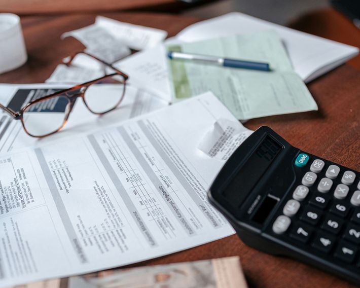 Desk with bills, glasses, calculator, and pen, suggesting financial tasks.