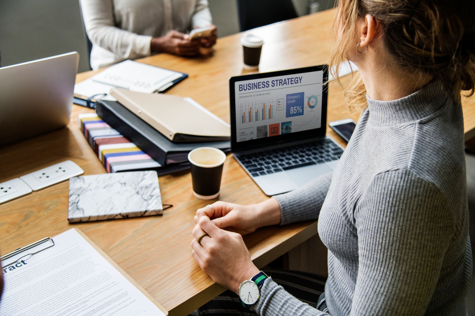 A woman is sitting at a table with a laptop on it.