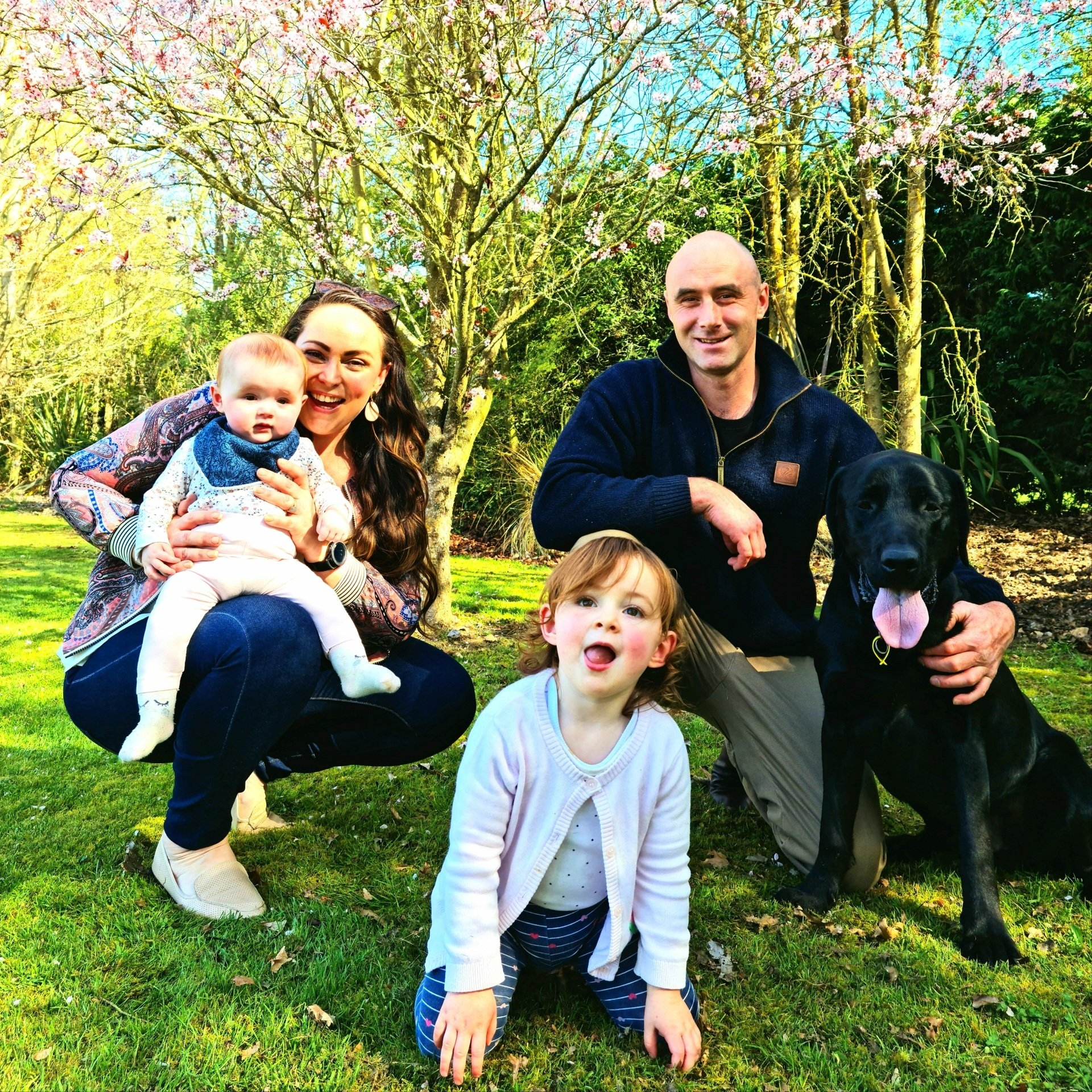 A family posing for a picture with a dog in a park.