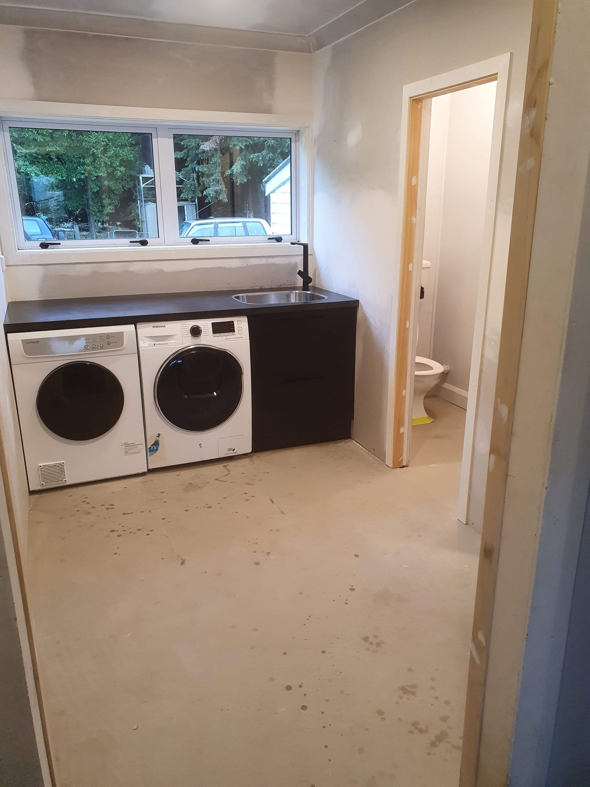A laundry room with a washer and dryer and a toilet.