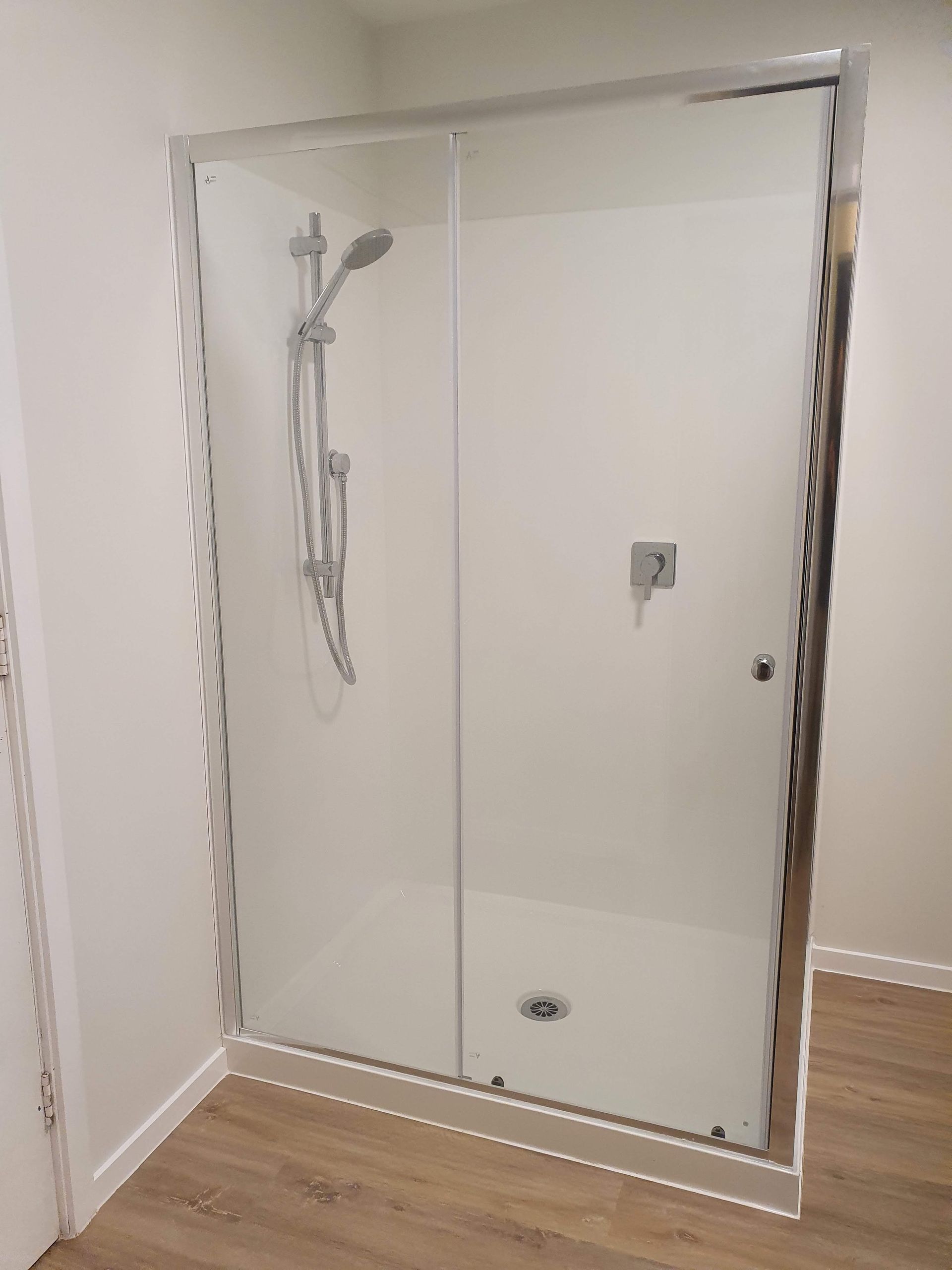 A shower stall with a sliding glass door and a shower head in a bathroom.
