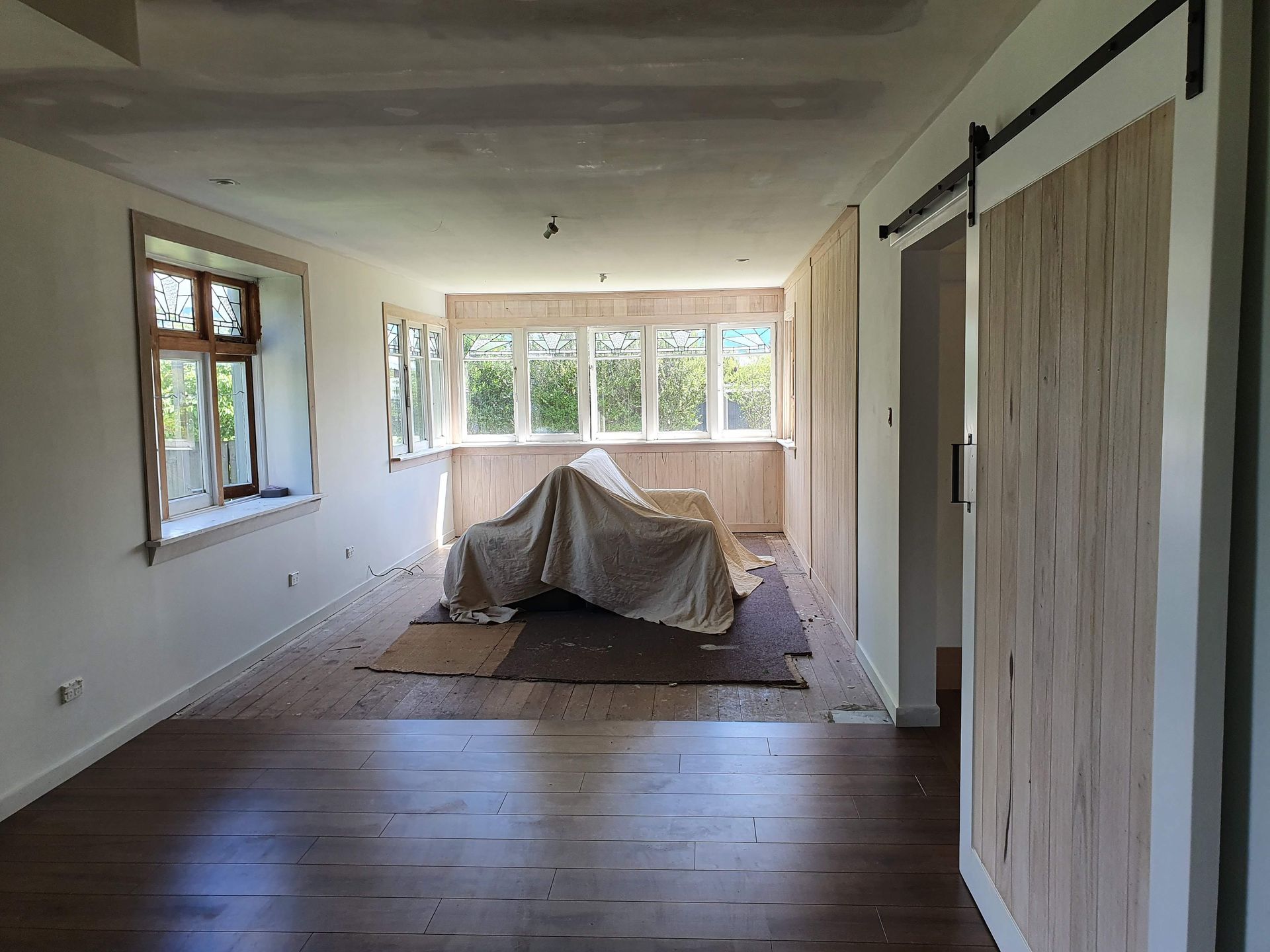A large empty room with hardwood floors and sliding barn doors.