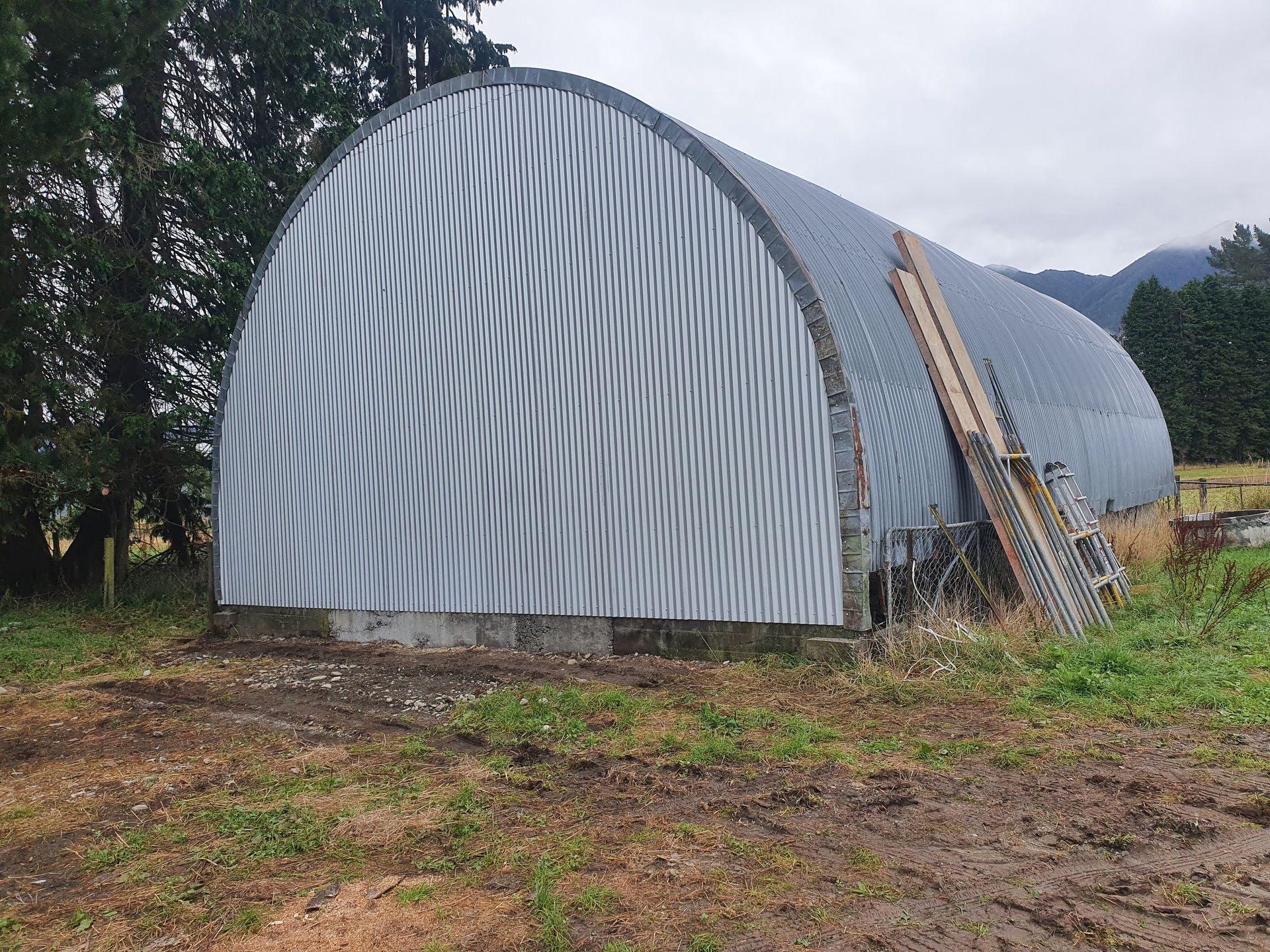 A large metal building is sitting in the middle of a field.